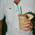 Man wearing The Surf No Turf white button-up shirt holding tropical drink with pineapple garnish