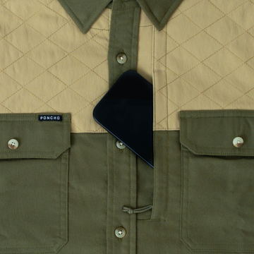 Close-up of The Roosevelt outdoor shirt pocket holding a phone, showing quilted and solid fabric design
