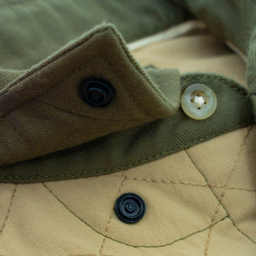 Close-up of green and tan quilted fabric with buttons on The Roosevelt shirt