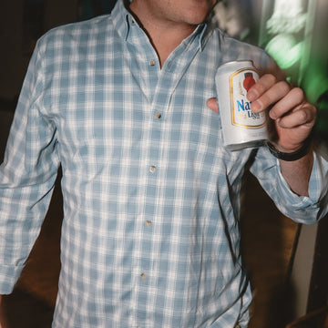 Man hanging out while wearing a blue button down fishing shirt