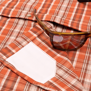 The Alamosa orange plaid outdoor shirt with sunglasses resting on the chest pocket