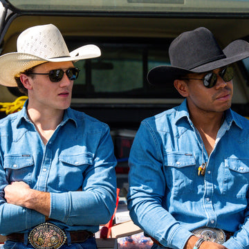 Two cowboys wearing denim shirt in the back of a truck