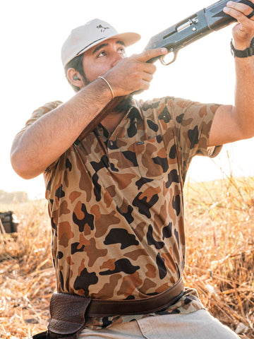 man shooting shotgun wearing camo polo shirt