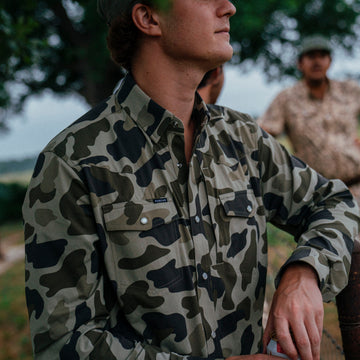 The Entre Rio camouflage shirt worn outdoors with blurred figures in background