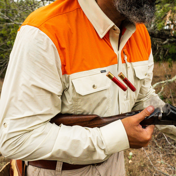 shells flying out of shotgun with man wearing long sleeve tan blaze patch shirt