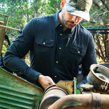 man working on tractor wearing black long sleeve shirt