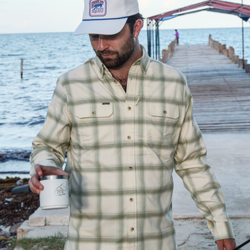 man wearing green and white plaid flannel holding cup