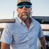 man driving boat in blue and grey plaid short sleeve