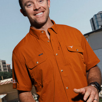 Man wearing The San Jacinto rust-colored outdoor shirt holding a football outdoors
