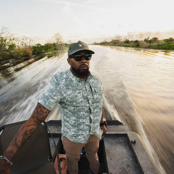 Man wearing The Chicken on a Hook shirt on a boat ride through a swamp at sunset
