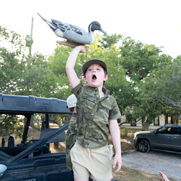 Kid holding duck in camo shirt