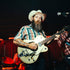 Man wearing The Frontman striped shirt and cowboy hat playing electric guitar on stage