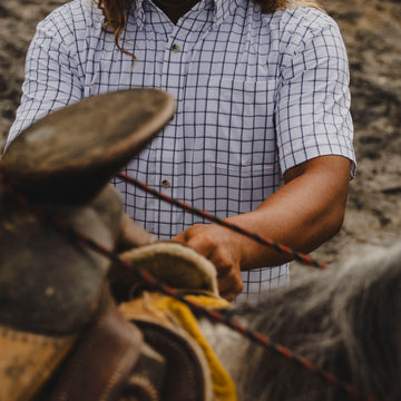 Man Saddling horse in short sleeve button down shirt