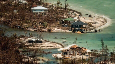 Aerial view of flooded coastal area with damaged houses and scattered debris