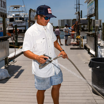 Man wearing The Surf No Turf shirt outdoors on dock with hose.
