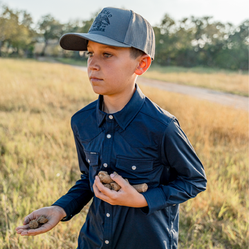 Boy holding cattle feed on a farm in navy pearl snap shirt