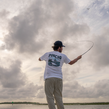 Man casting a fly rod while wearing The Sport Fisher T-shirt