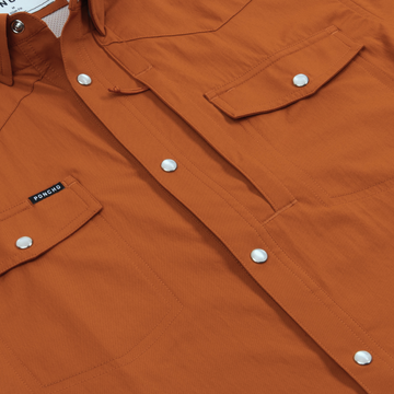 Close-up of rust orange button-up shirt with snap pockets showing The 1969 label