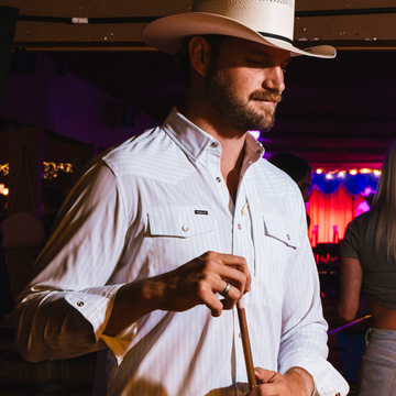 man wearing the two step shirt holding pool cue