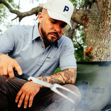 man cooking wearing the 2 stroke performance polo