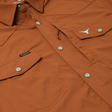 Close-up of rust-colored shirt with snap buttons and flap pockets from The Bertha collection