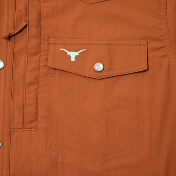 Close-up of burnt orange pocket with snap button and white logo on The Bertha shirt