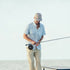 Man outdoors fishing wearing The Bow To The King shirt and beige pants