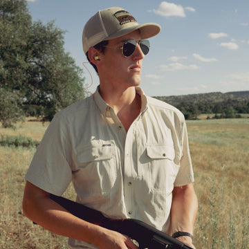 man wearing the brown bear shirt holding shotgun