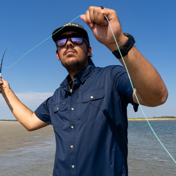 Man casting a fly rod in a navy shirt