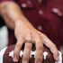 Close-up of a hand wearing The College Station ring resting on a football with a maroon shirt in the background