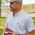 Man outdoors wearing The Eye of the Tiger white shirt holding football