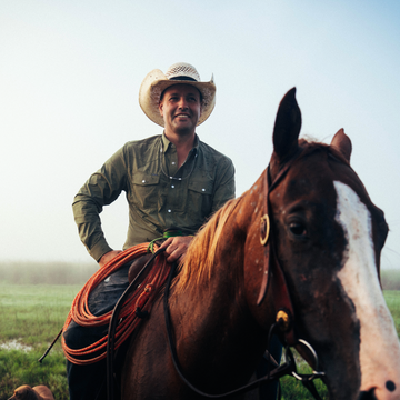 man riding horse wearing green long sleeve shirt