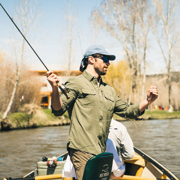 Man fishing on river wearing The Gunnison outdoors shirt