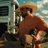 Man wearing The Joshua Tree shirt holding a saddle outdoors
