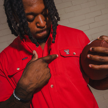 man holding football with red texas tech embroidered shirt