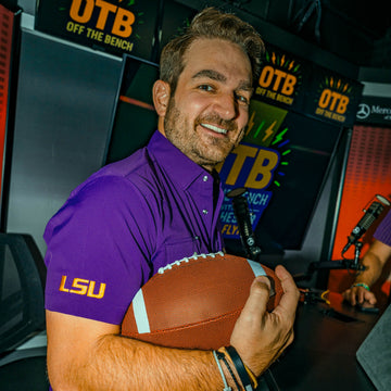 man holding football wearing purple LSU shirt