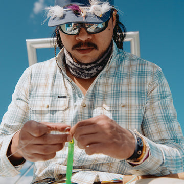 Man tying on a fly while wearing the Nervous Water shirt