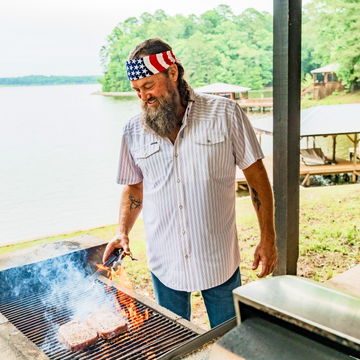 man wearing the old glory grilling steaks