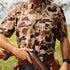 Man wearing The Paloma camo shirt holding a shotgun outdoors