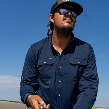 Man fly fishing while wearing a navy shirt