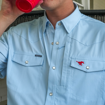 Man wearing light blue shirt with snap buttons and embroidered red horse logo drinking from a red cup, featuring The Pony Up branding.