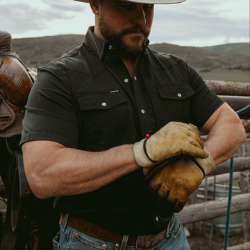man tightening work gloves while wearing black shirt
