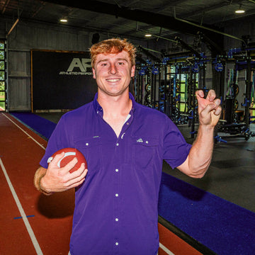 man wearing purple TCU shirt holding football