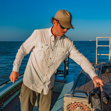man grabbing fishing rods wearing the skiff shirt