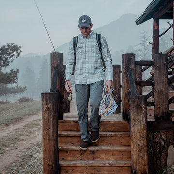 Man wearing The Snowcat plaid shirt while fly fishing outdoors