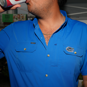 Man wearing a blue The Swamp Chomp shirt drinking a beverage outdoors at night