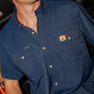 Close-up of a navy blue button-up shirt with embroidered logo on chest pocket called The War Eagle