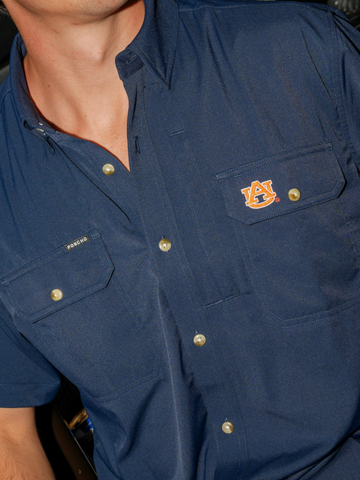 Close-up of a navy blue button-up shirt with embroidered logo on chest pocket called The War Eagle