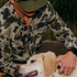 Man wearing The Zenaida camo shirt outdoors petting a yellow Labrador retriever dog