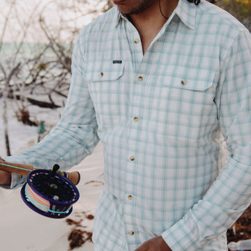 man holding fly rod on beach in the 12 weight shirt